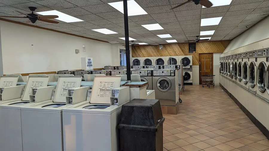Self-service laundromat interior with rows of washing machines and dryers